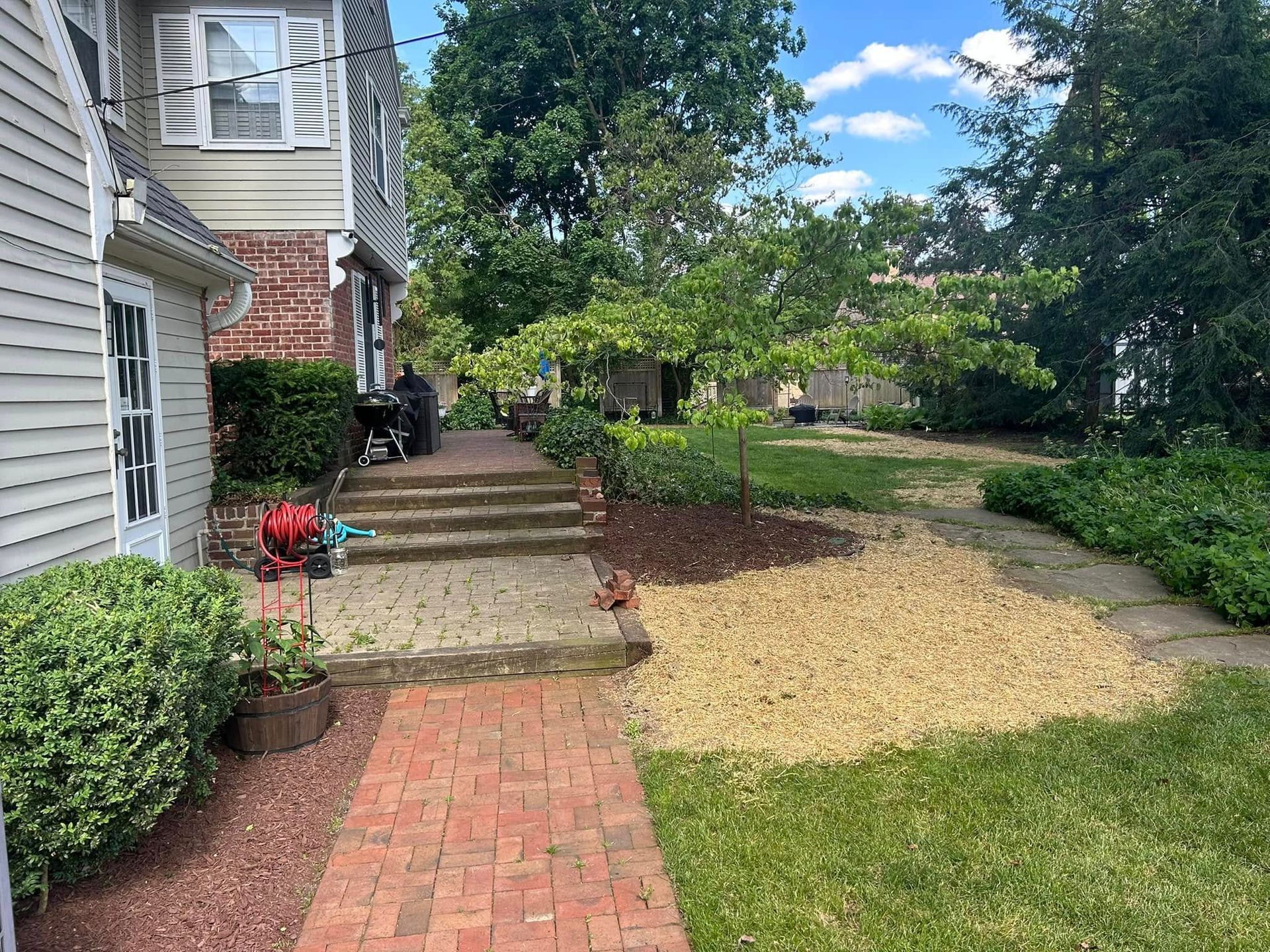 Brick pathway and steps leading to a house with a yard of grass and decorative gravel. Sunny day.