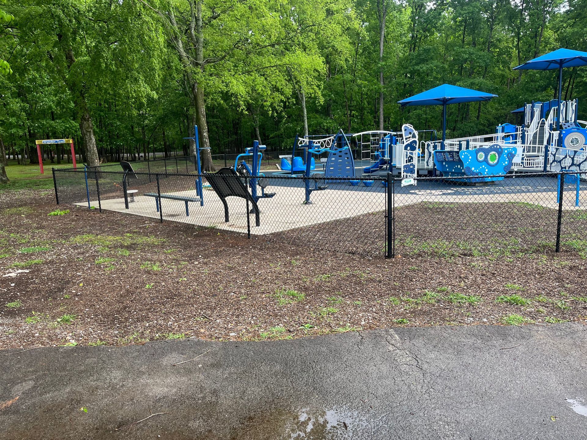A playground with a bench and umbrellas in a park.