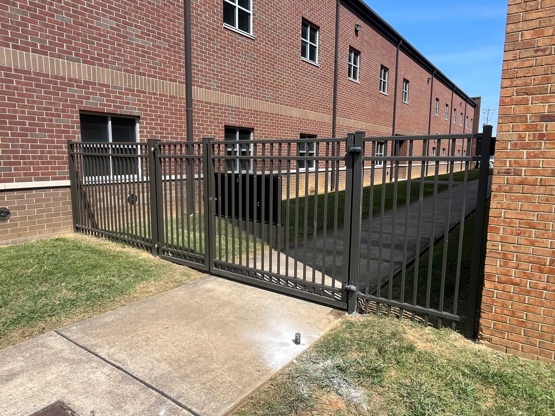 A shadow of a person is cast on a grassy field in front of a building.