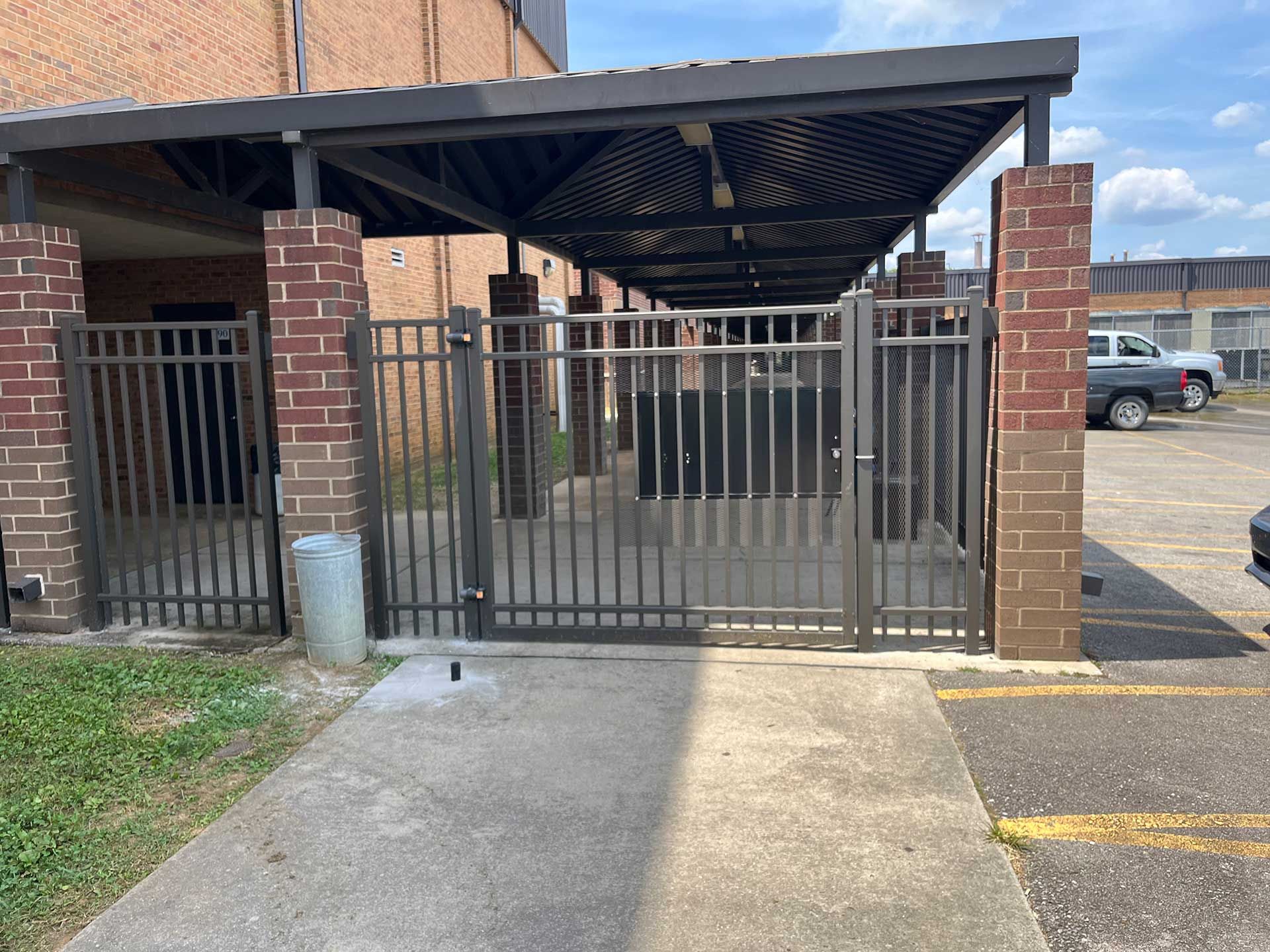 A brick building with a fence and a car parked in front of it