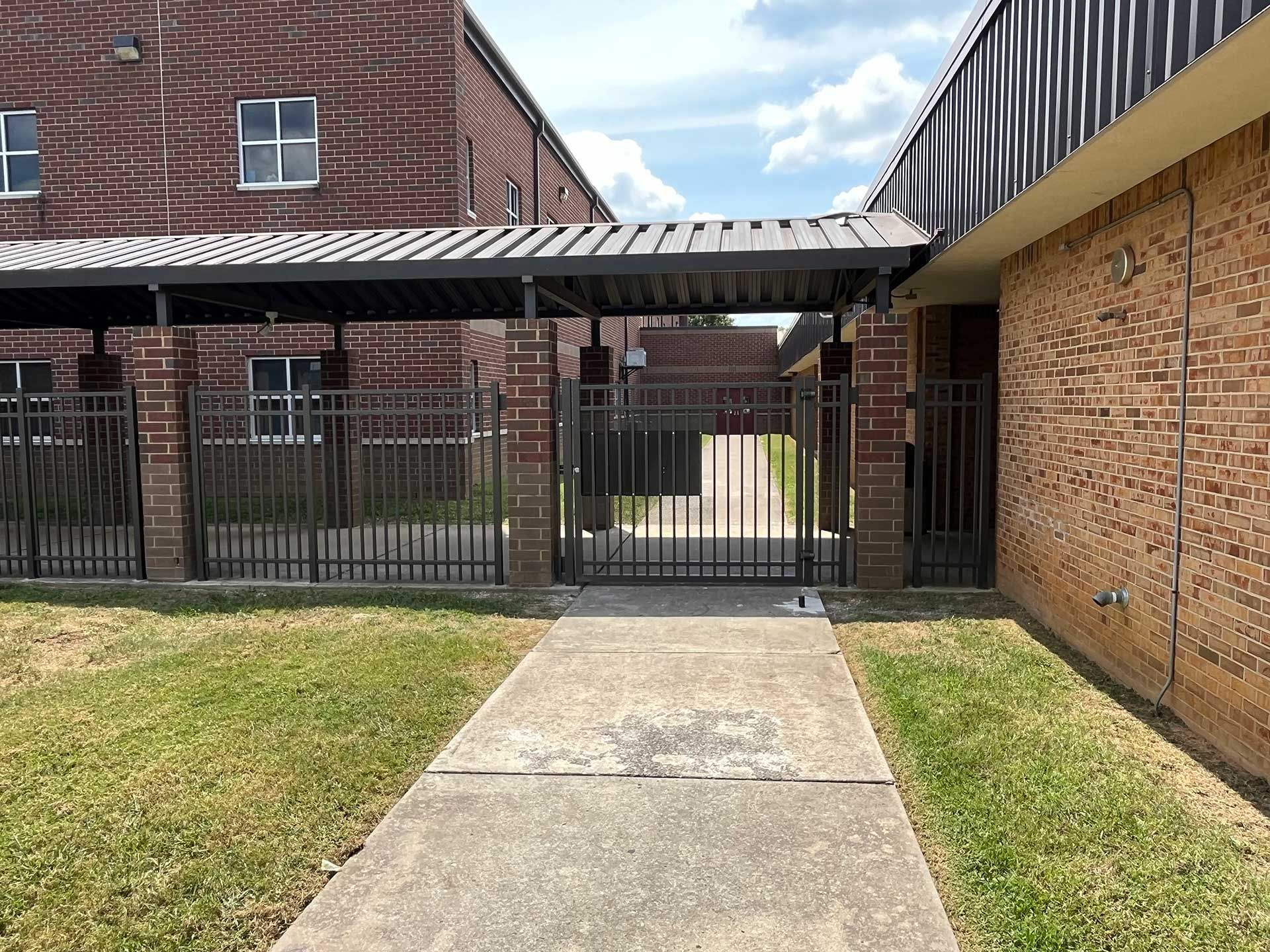 A brick building with a fence and a walkway leading to it