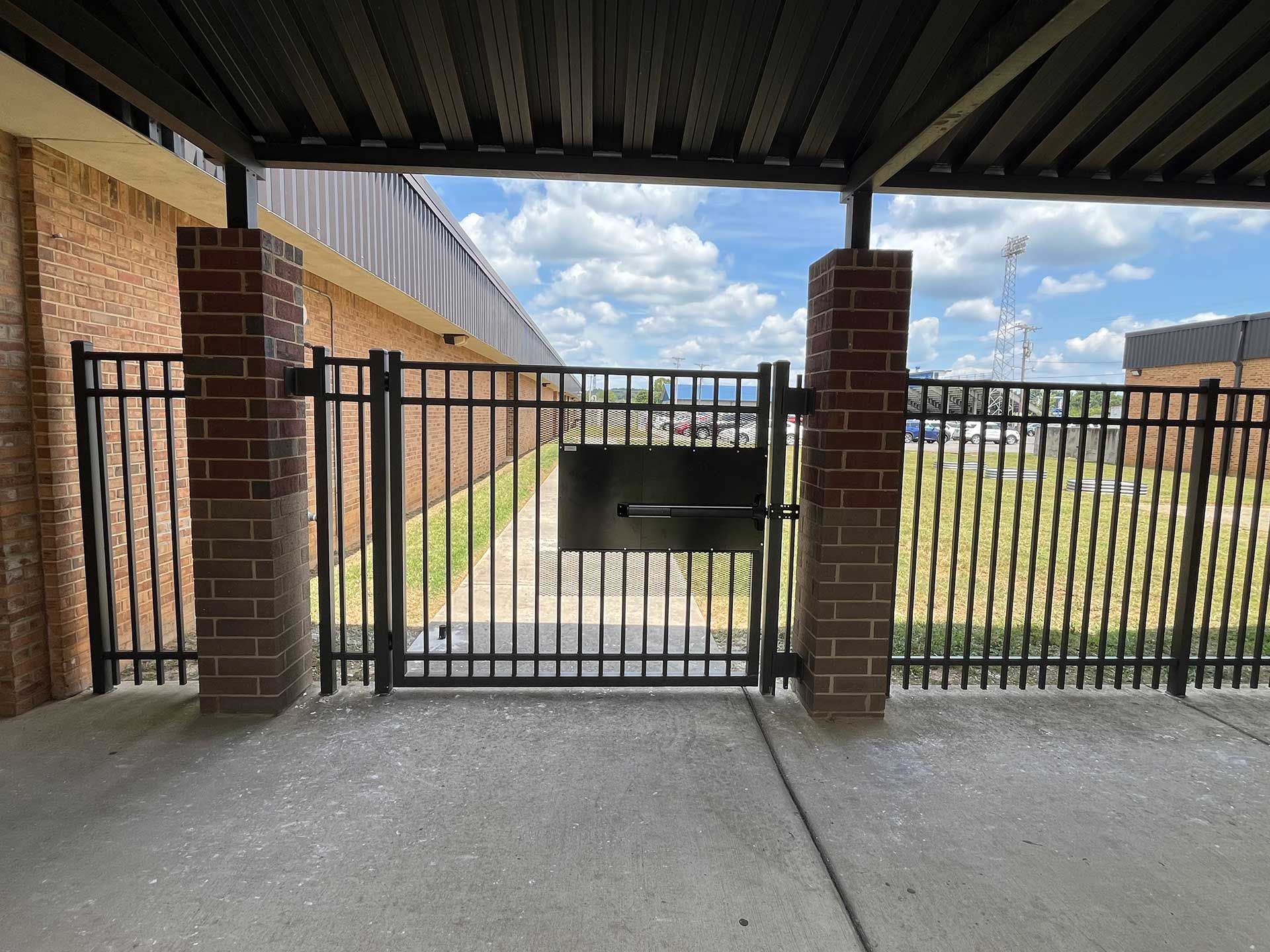 A fence with a walkway leading to a field