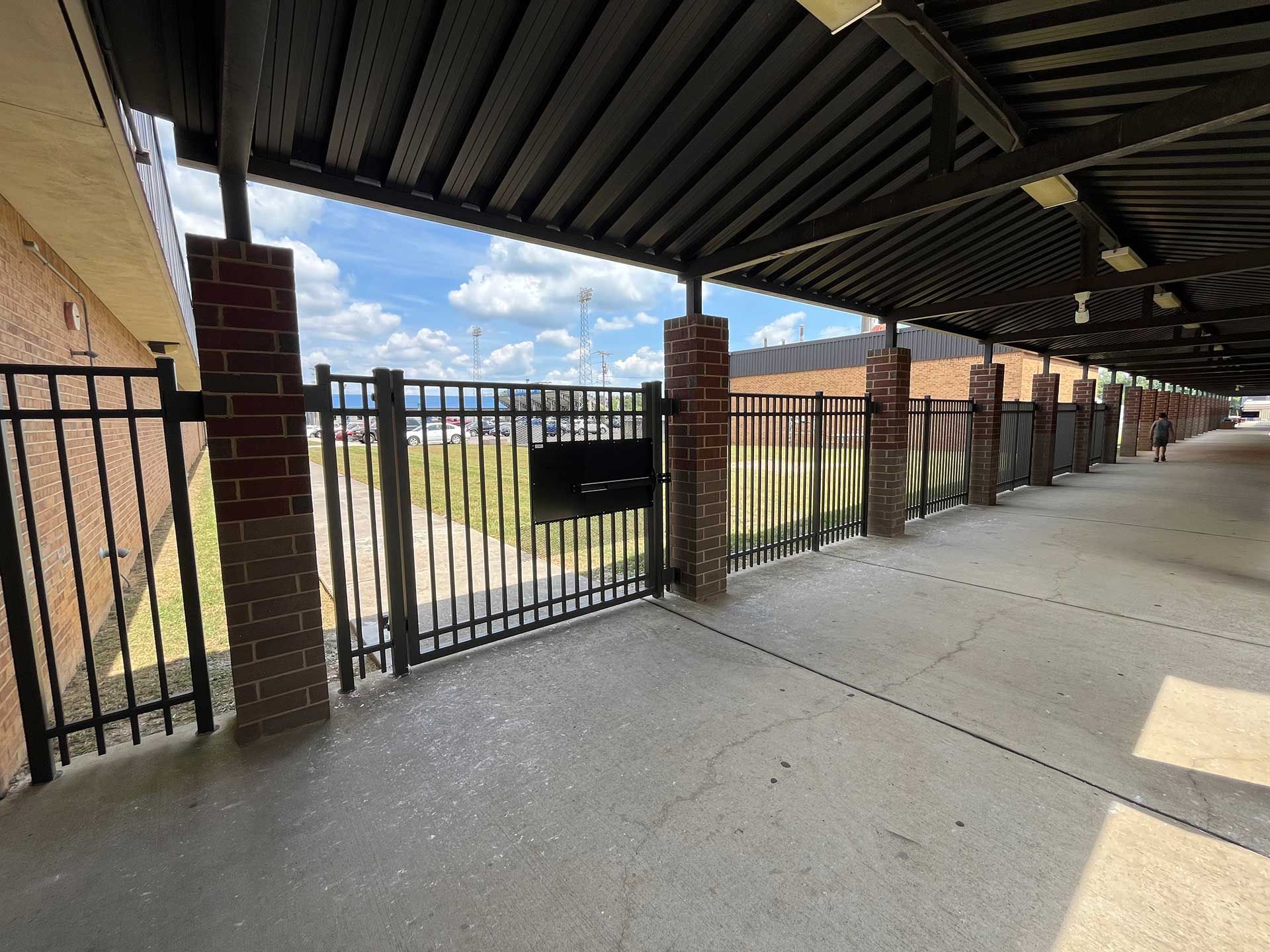 a covered walkway with a fence and brick posts