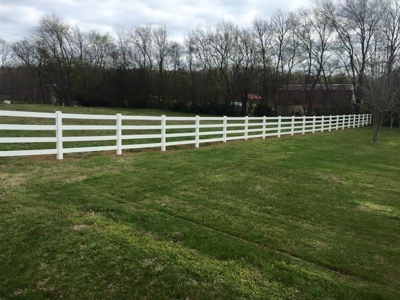 a white fence surrounds a lush green field
