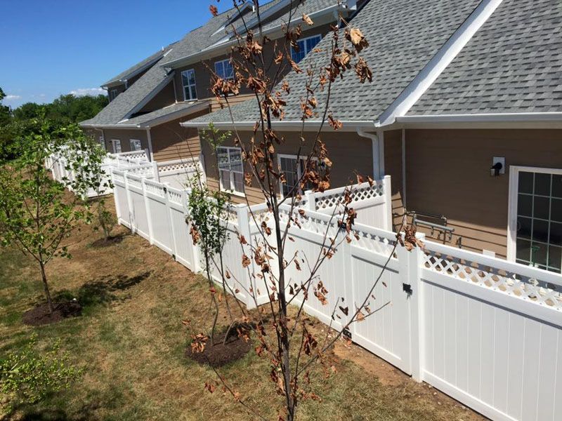 a white fence surrounds a lush green yard in front of a house