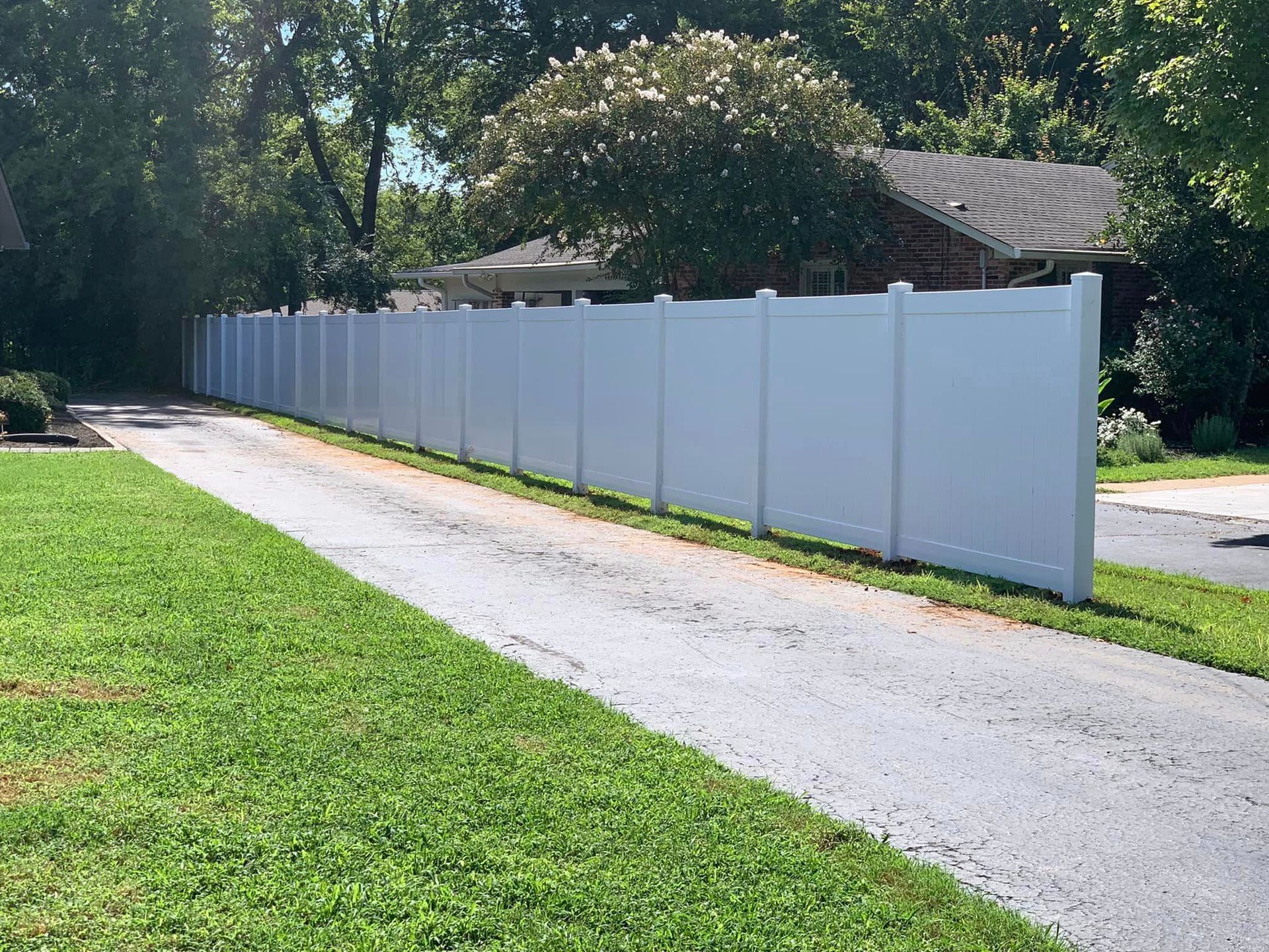 a white fence along a driveway leading to a house