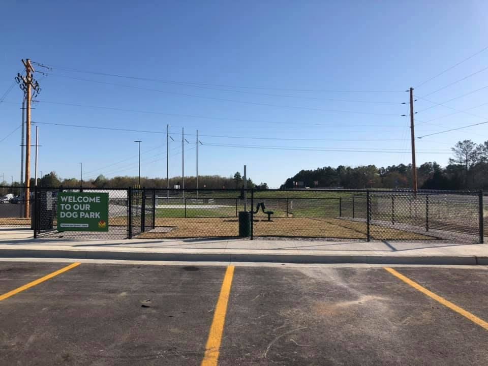 a parking lot with a fence and a sign that says welcome to the dog park