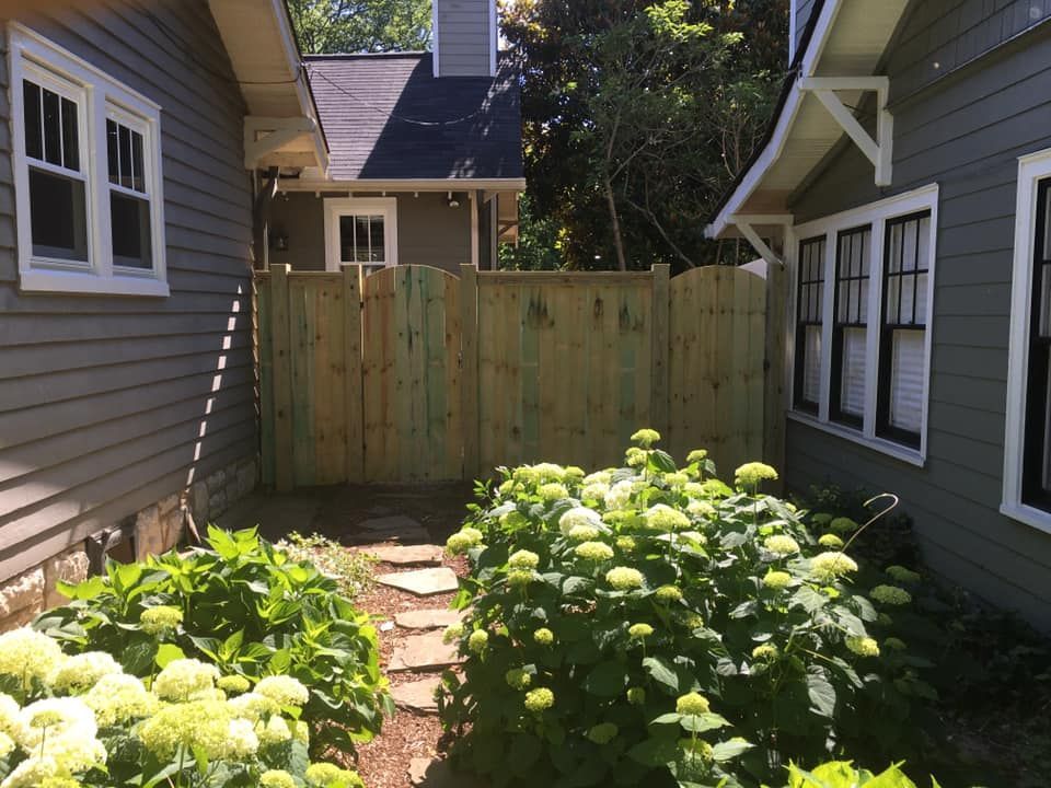 a house with a wooden fence and flowers in front of it
