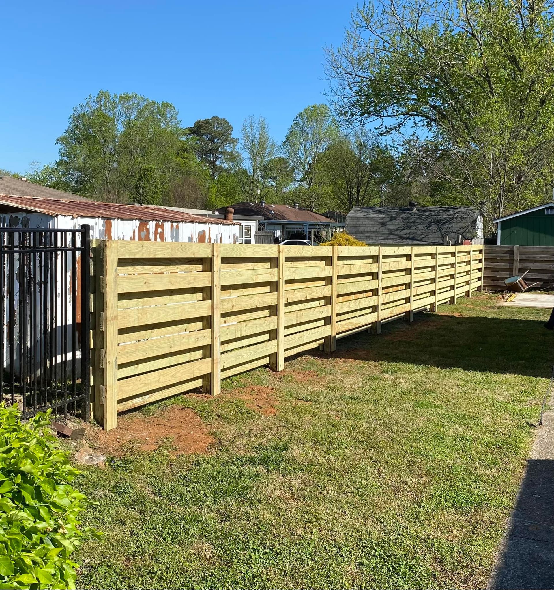 a wooden fence is in the middle of a grassy yard