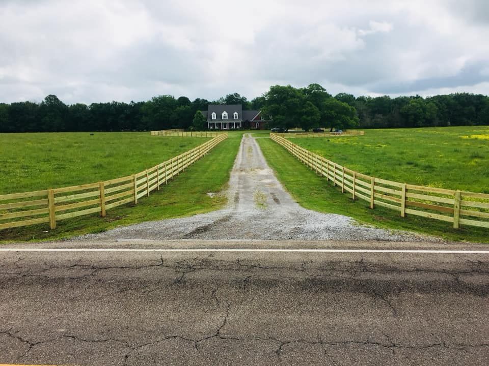 a driveway with a wooden fence leading to a house