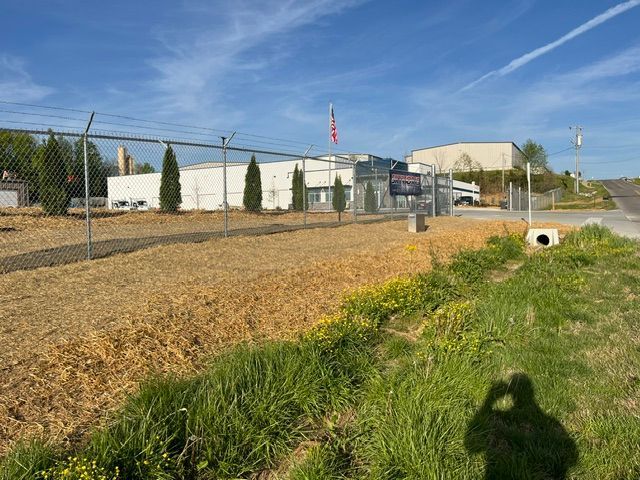 A shadow of a person is cast on a grassy field in front of a building.