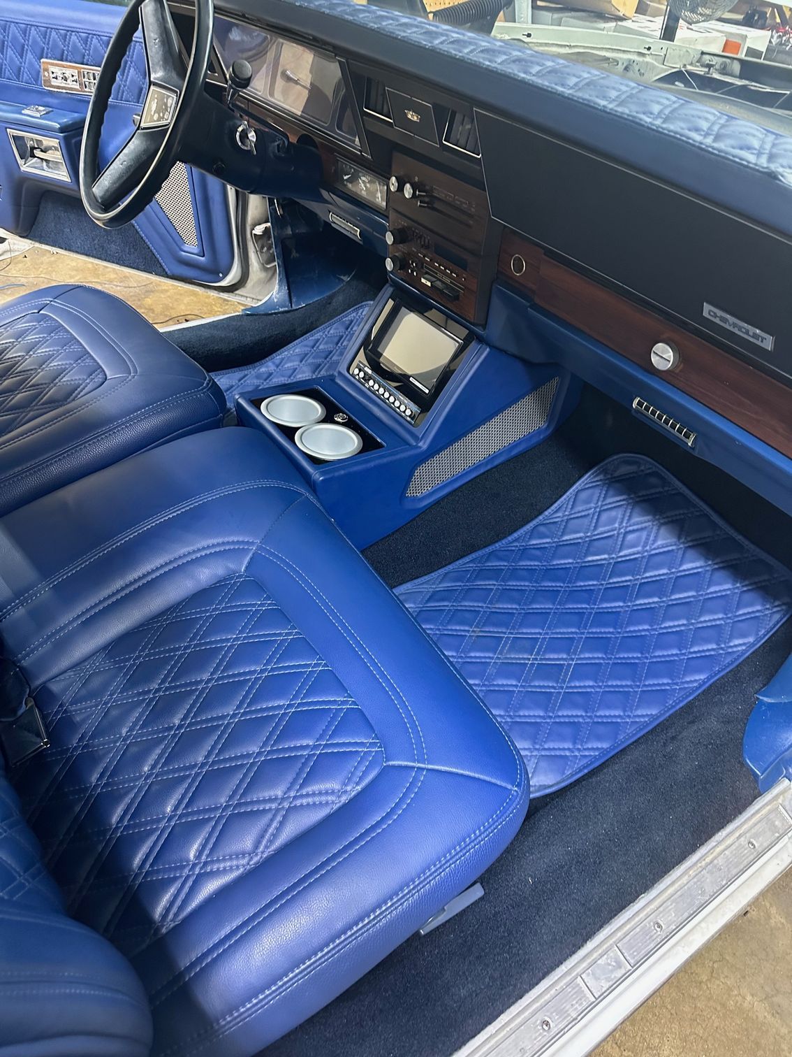 Blue car interior with diamond-stitched leather seats, a center console, and matching floor mats.