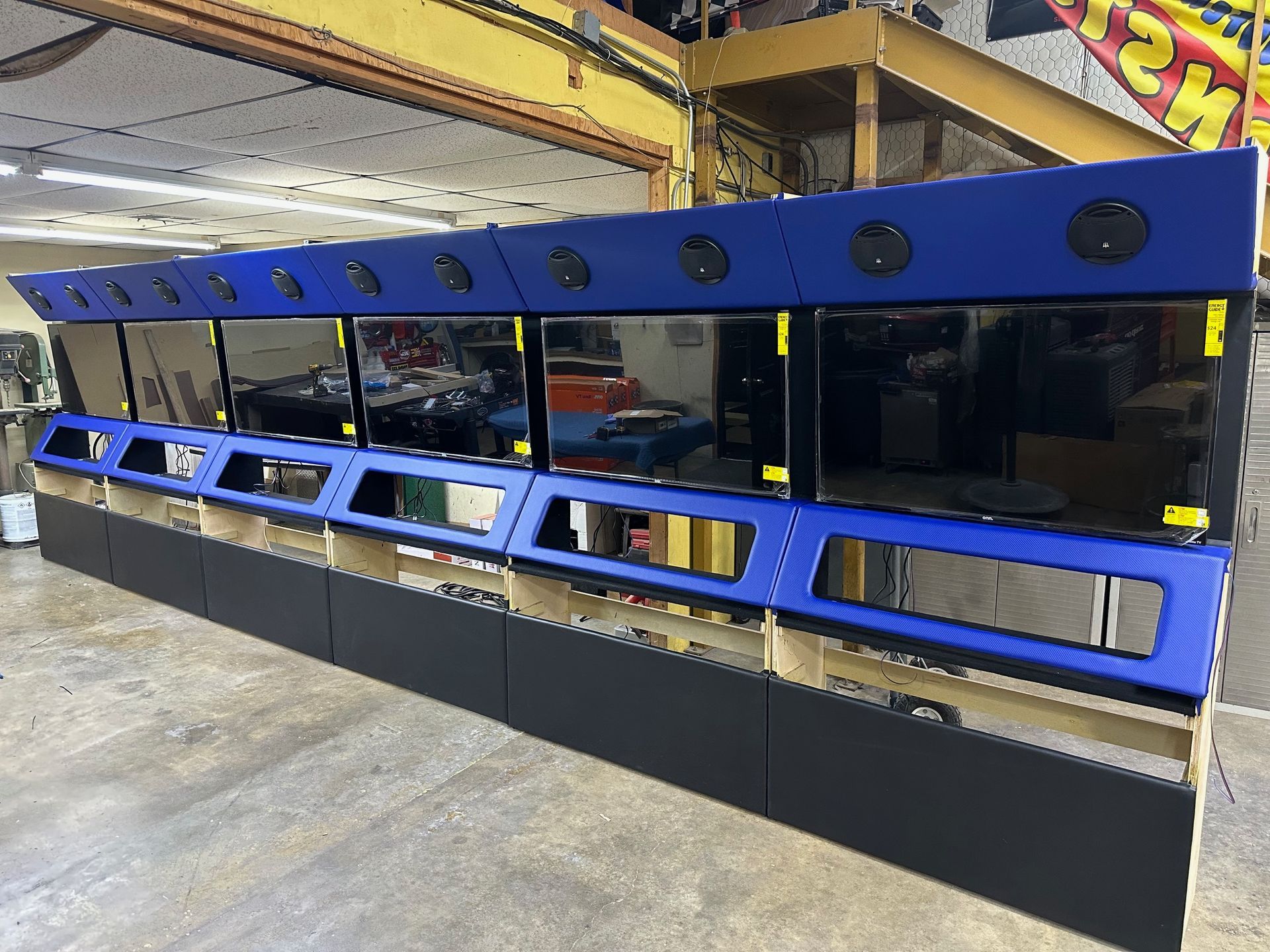 Large display console with blue and black panels, multiple screens, and circular vents, in a workshop setting.