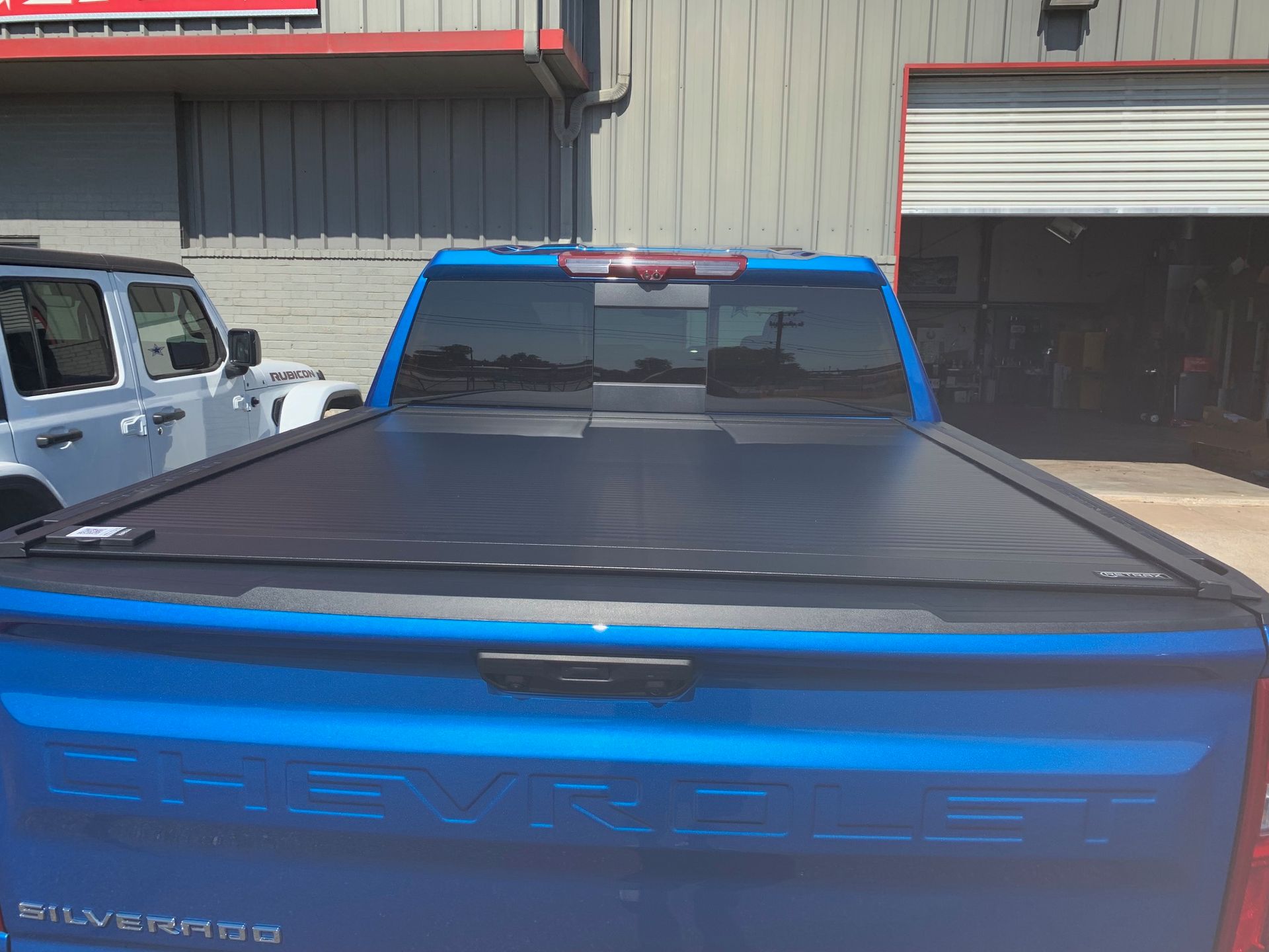 Blue Chevrolet Silverado pickup truck with black bed cover parked outside a building.