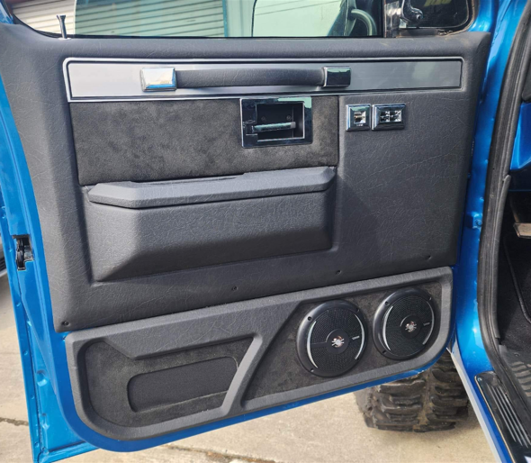 Blue truck door with black and silver interior. Two speakers are in the lower panel.
