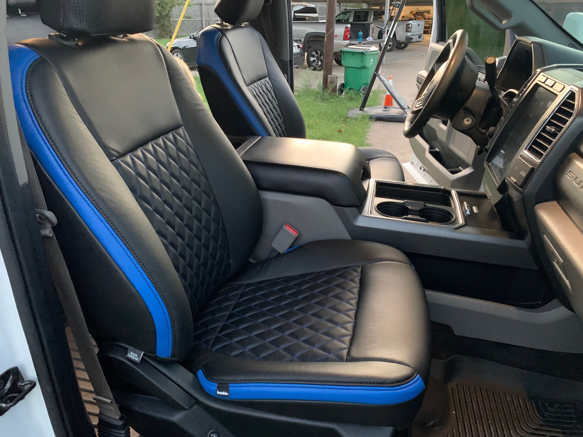 Black and blue leather truck seats with diamond stitching, center console, and steering wheel.