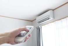 a person is holding a remote control in front of an air conditioner