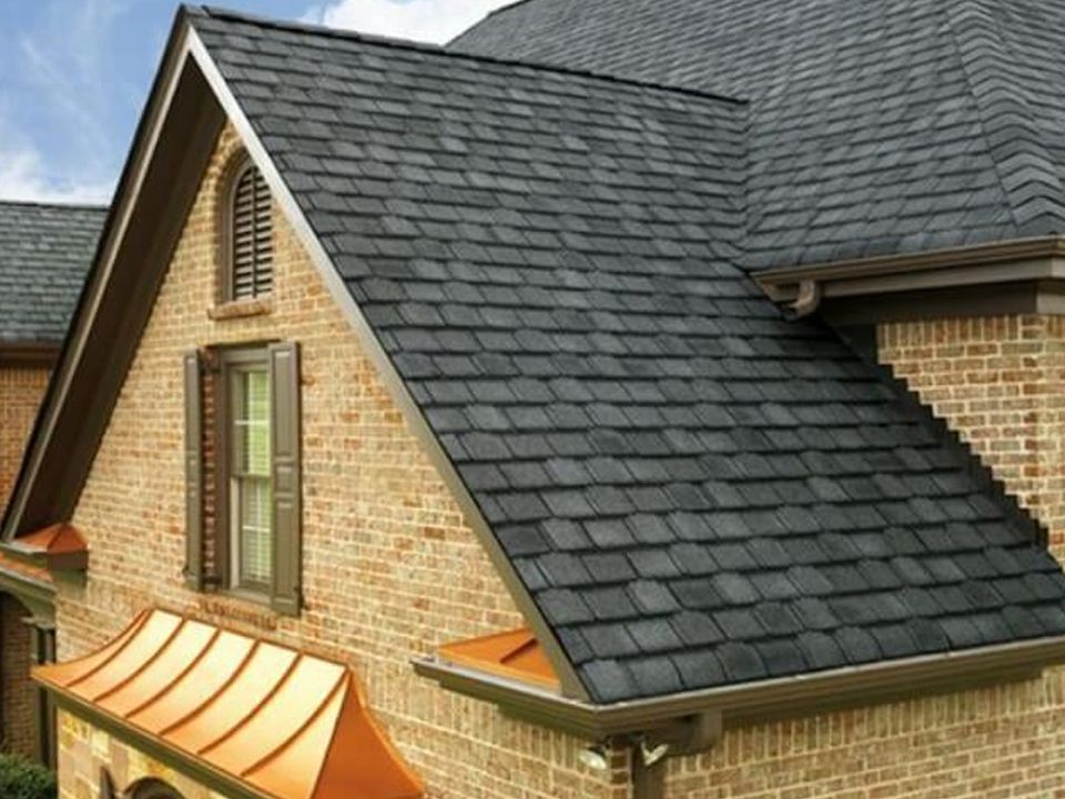 Brick house with dark gray shingle roof and copper gutters.