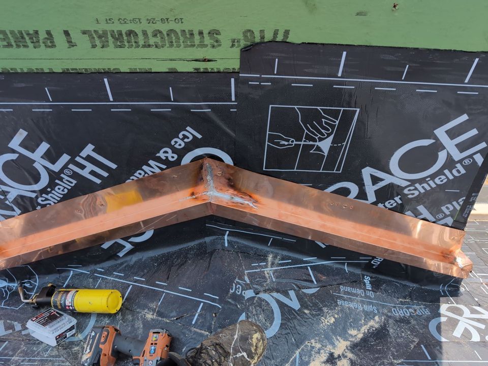 Copper flashing installed at roof corner, over ice and water shield.
