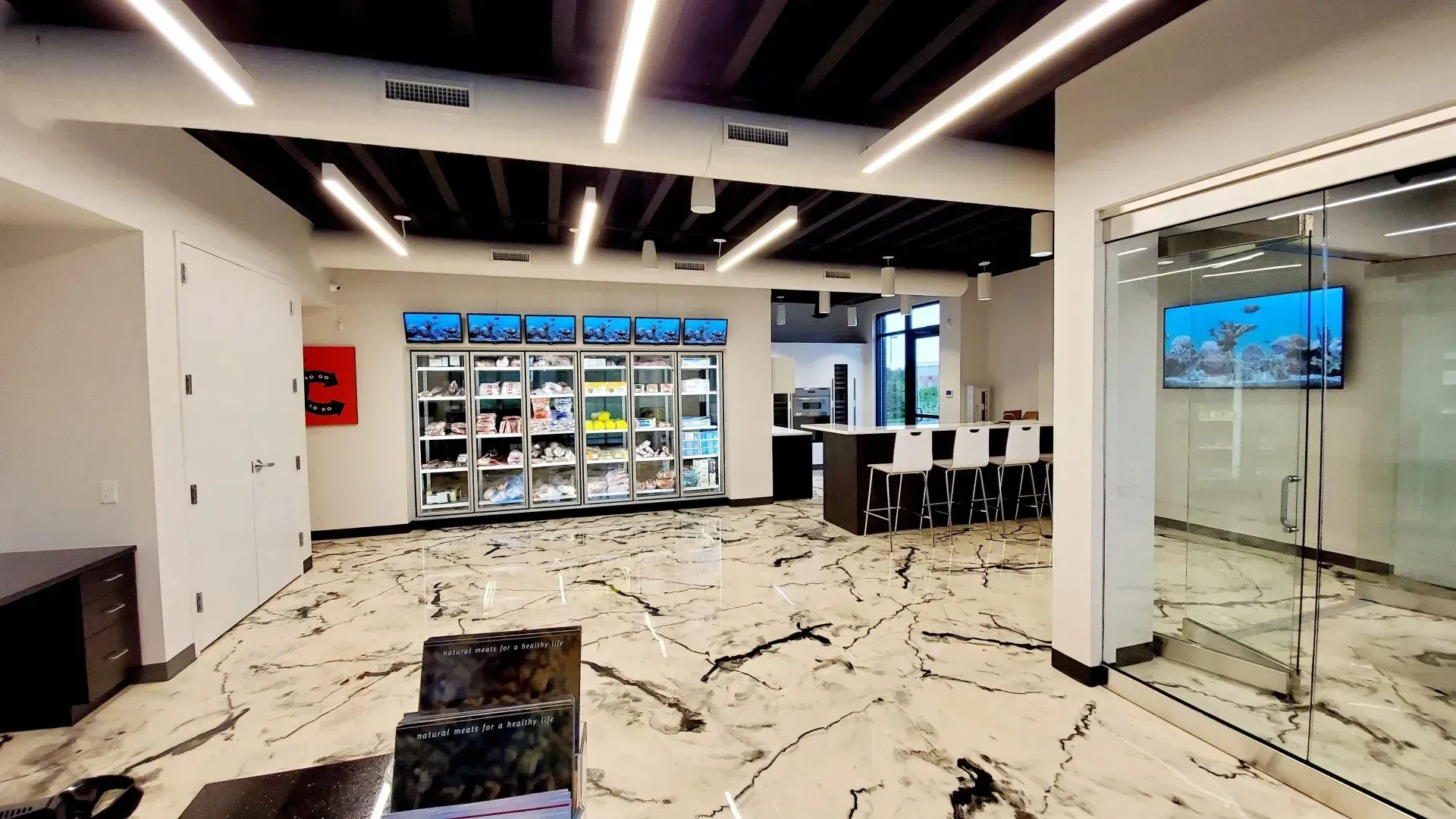 Interior of a store with display cases, marble floors, and glass doors; bright lighting.