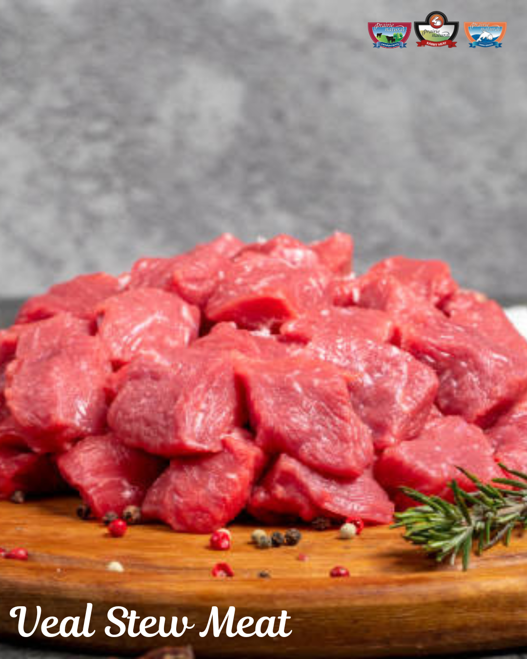 Close-up of raw veal stew meat cubes on a wooden board with rosemary and peppercorns.