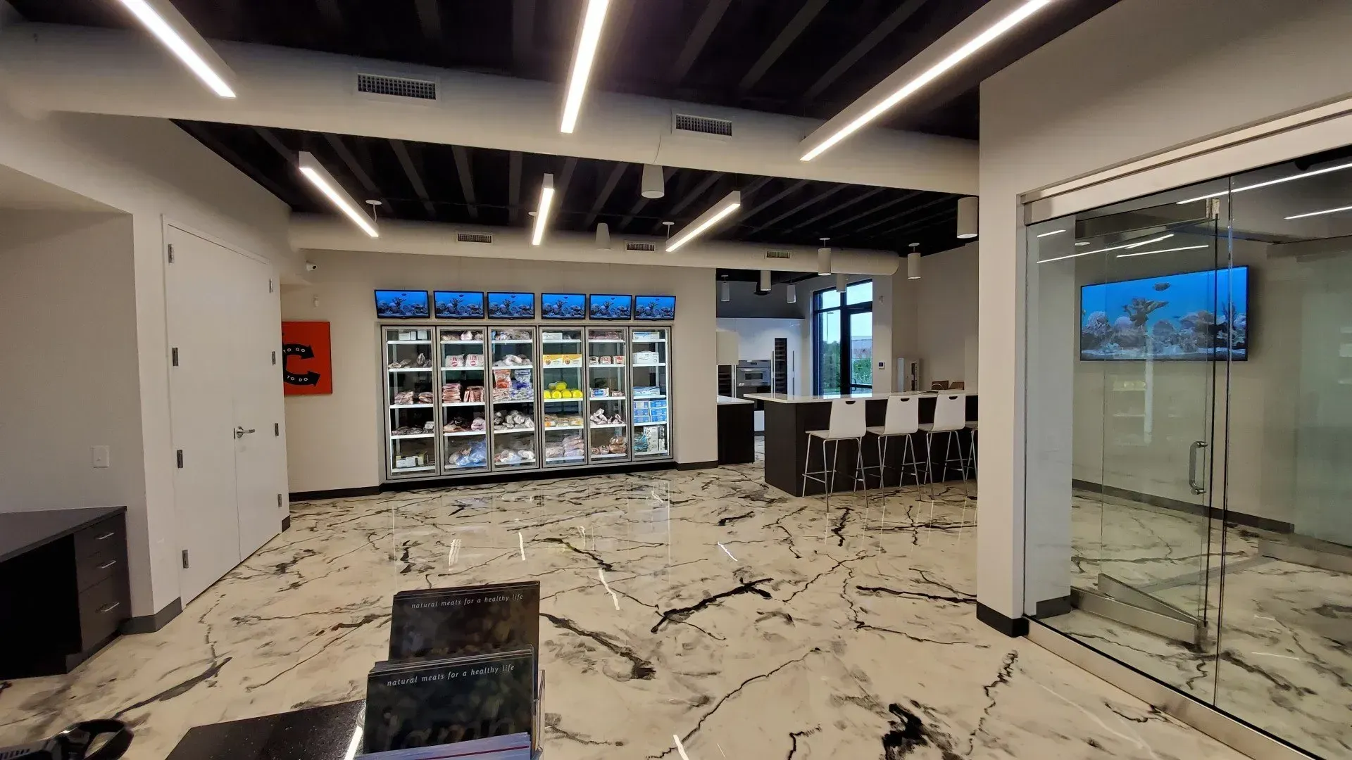 Modern office interior with shoe display, marble floor, bar seating, and a TV.