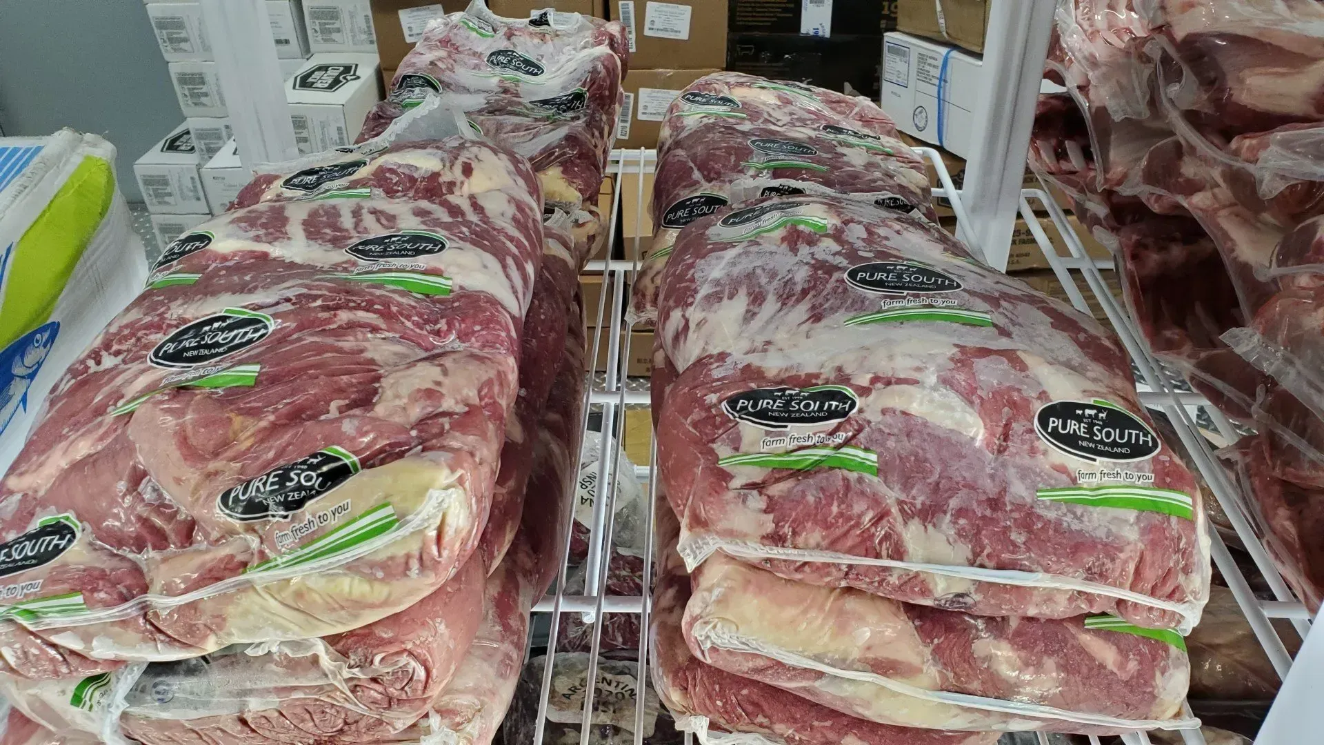 Packages of raw meat on display in a refrigerated shelf.