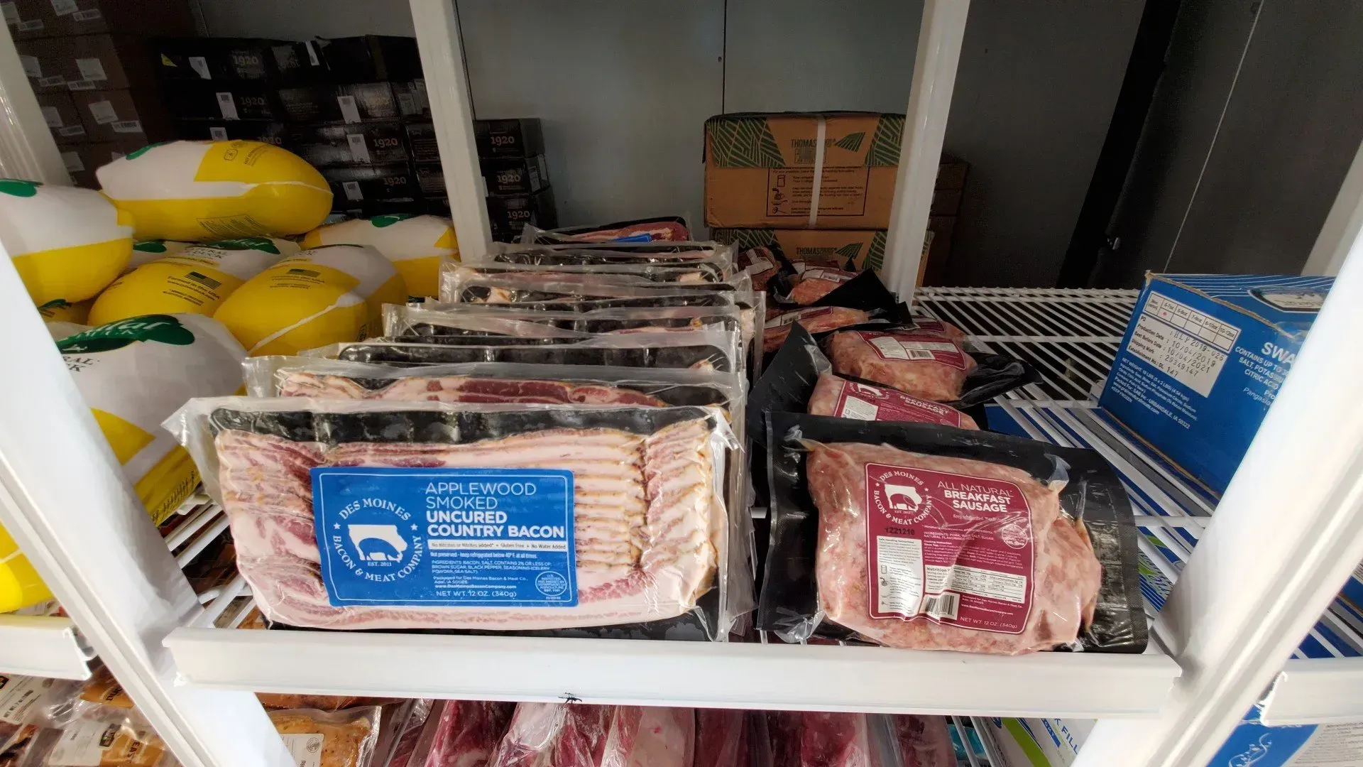 Refrigerator shelves stocked with packaged meats, including bacon, pork, and turkey.