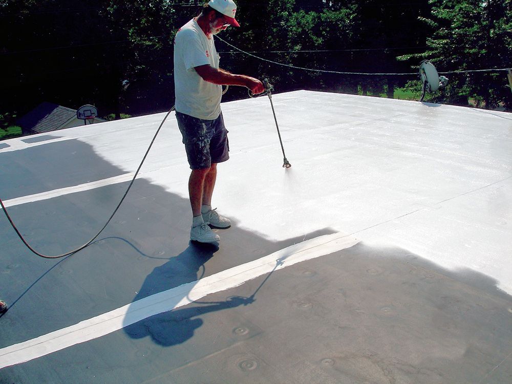 A man is spraying a roof with a sprayer