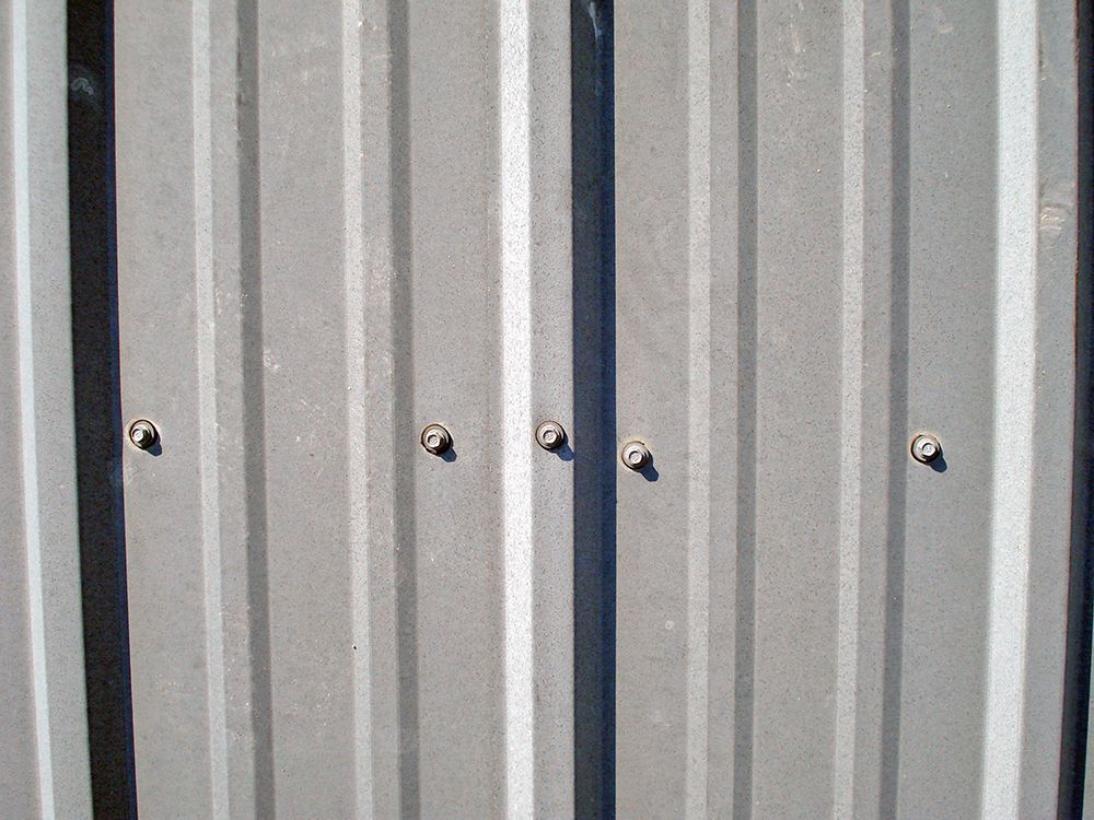 A close up of a metal wall with screws on it