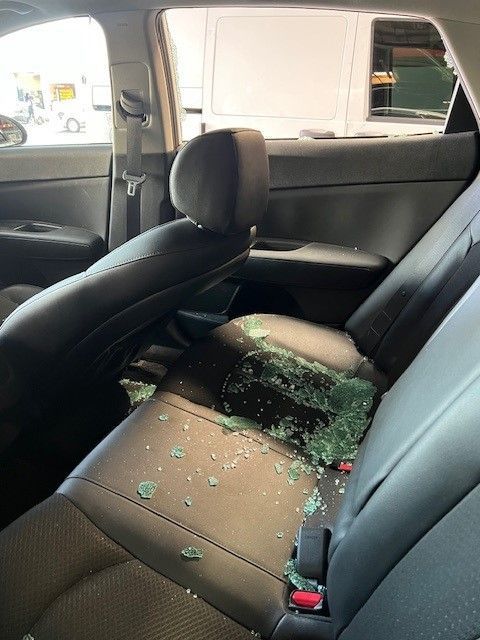 The back seat of a car with broken glass on it.