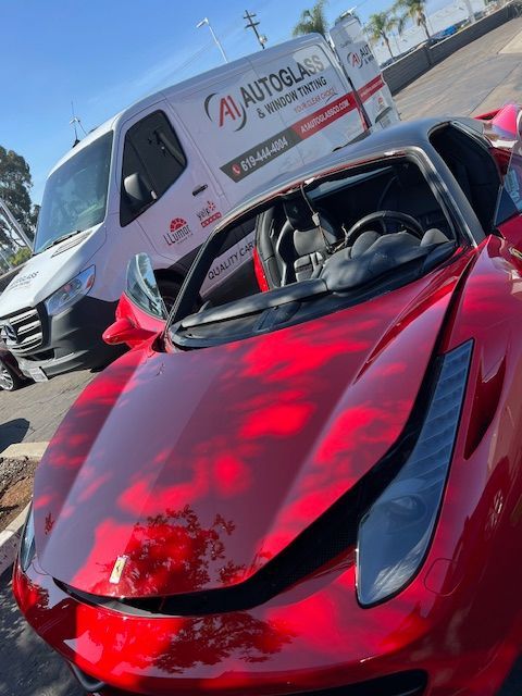 A red sports car is parked next to a white van that says autoglas