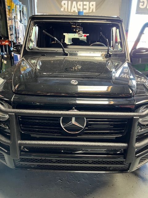 A black mercedes benz is parked in a garage.