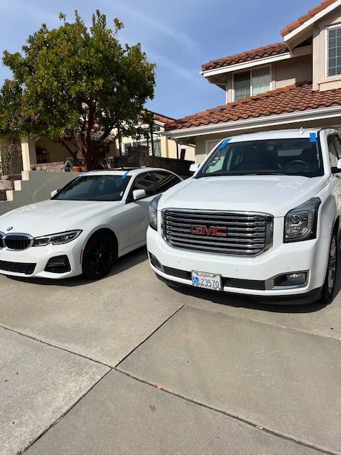 A bmw and a gmc are parked in front of a house