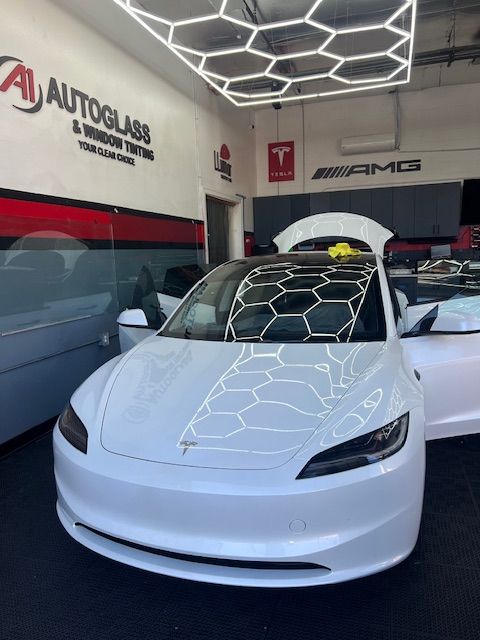 A white tesla model 3 is parked in a garage