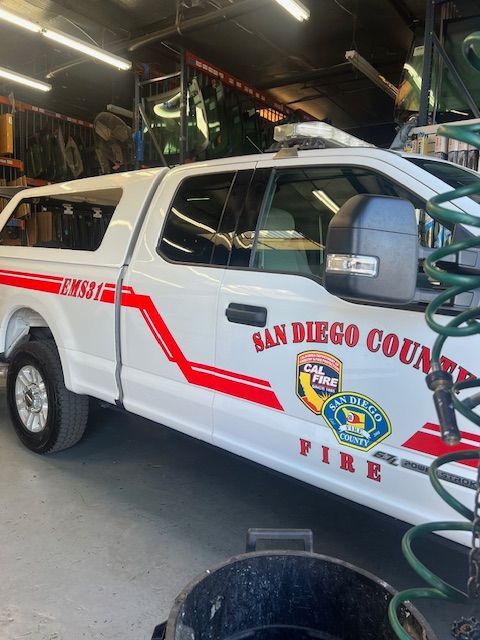 A white san diego county fire truck is parked in a garage