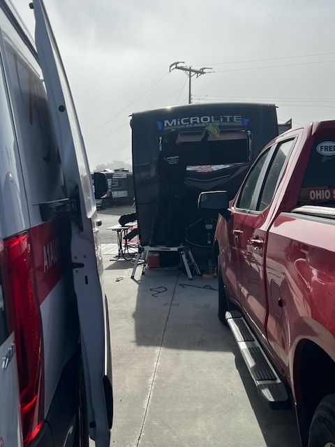 A red truck is parked next to a white van that says microlite