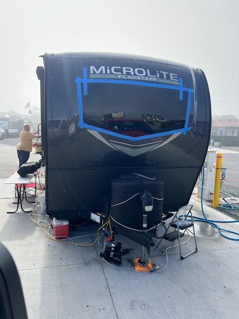 A black rv is parked in a parking lot.