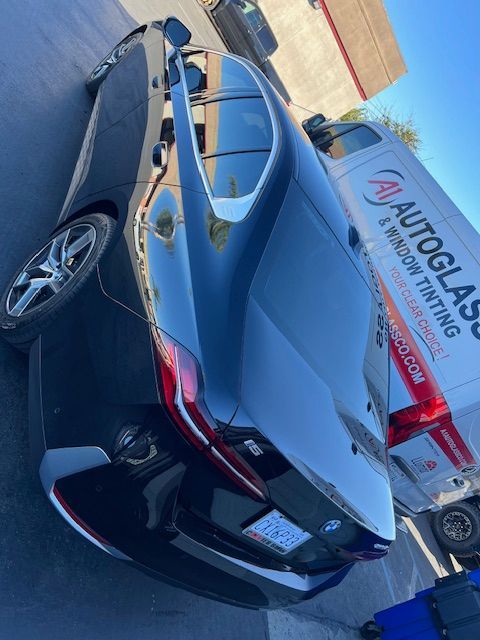 A car is parked next to an autoglass window tinting van