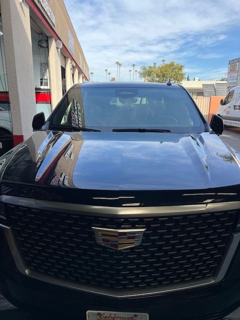 A black cadillac is parked in front of a building.