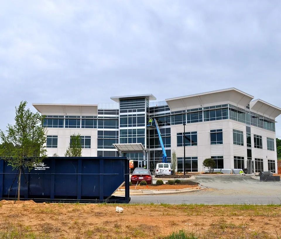 A large white building with a blue dumpster in front of it