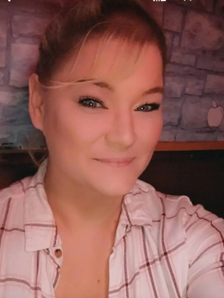 A woman in a plaid shirt is smiling for the camera.