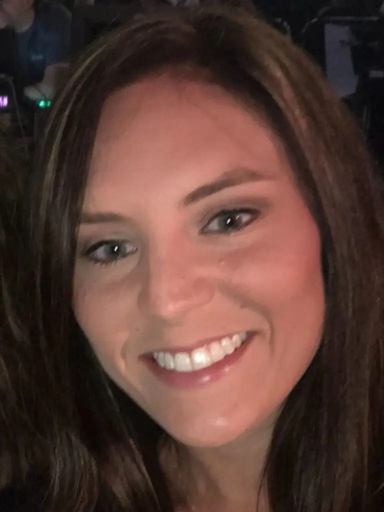 A woman with long brown hair is smiling for the camera.