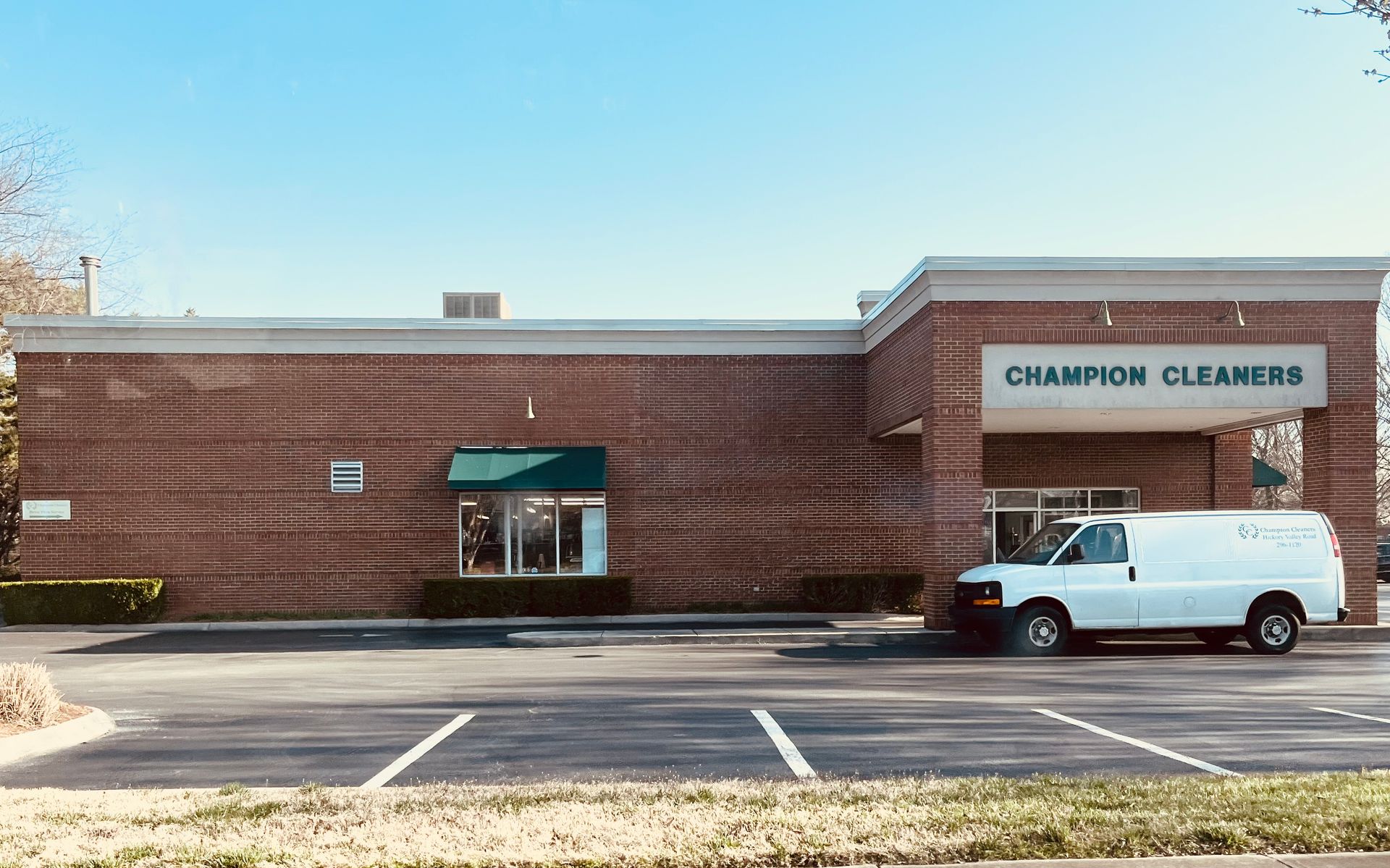 Champion Cleaners building with a white van in the parking lot on a sunny day.
