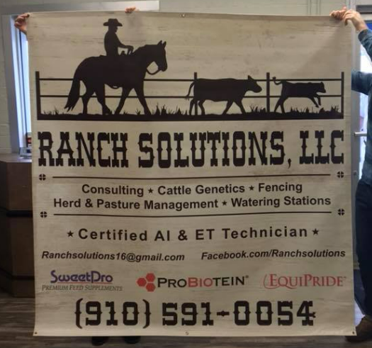 A man is holding a large sign for ranch solutions llc.