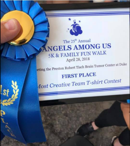 A person is holding a blue ribbon and a certificate for the 25th annual angels among us 5k & family fun walk.