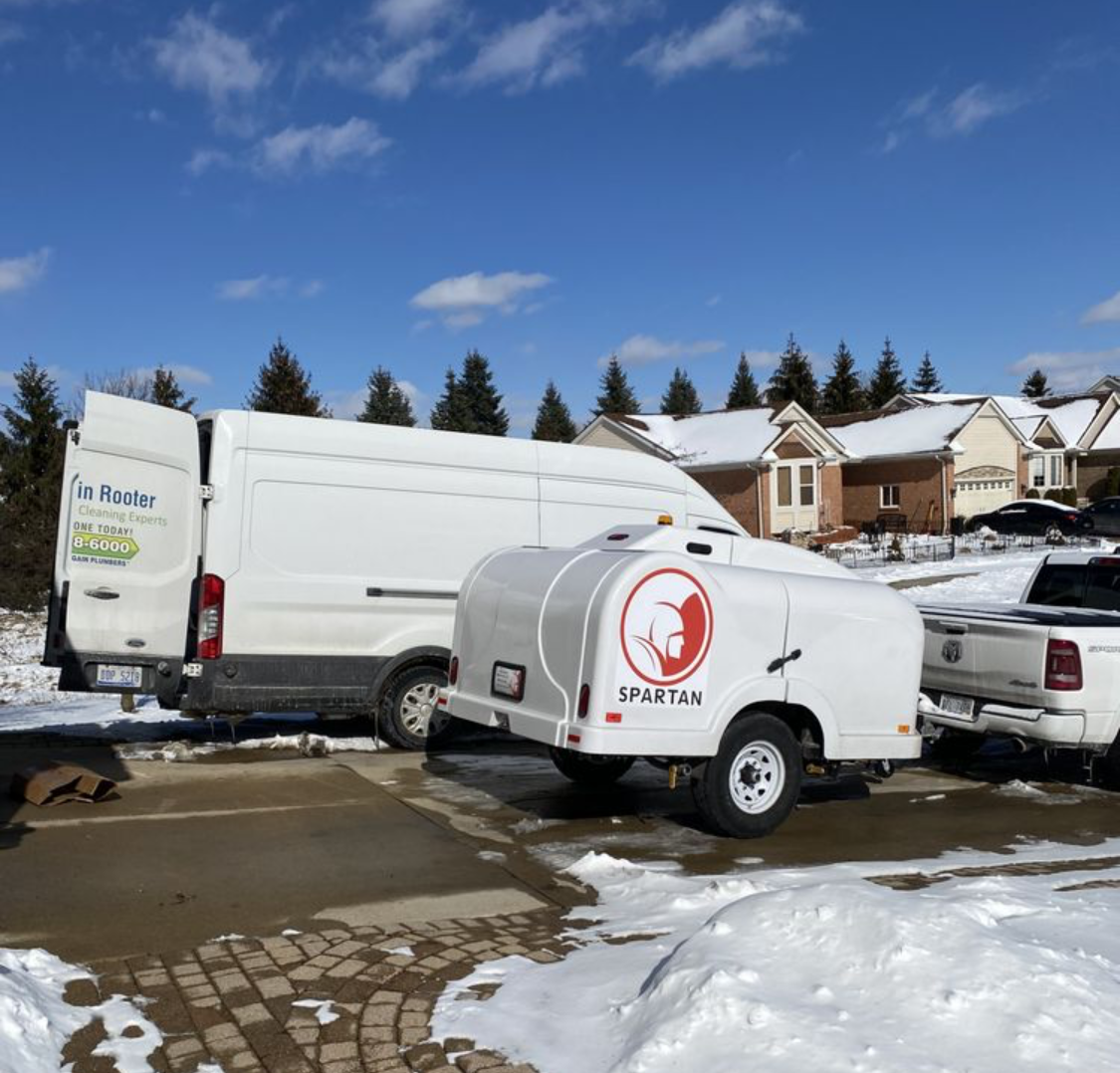 Two white vans are parked in a snowy parking lot