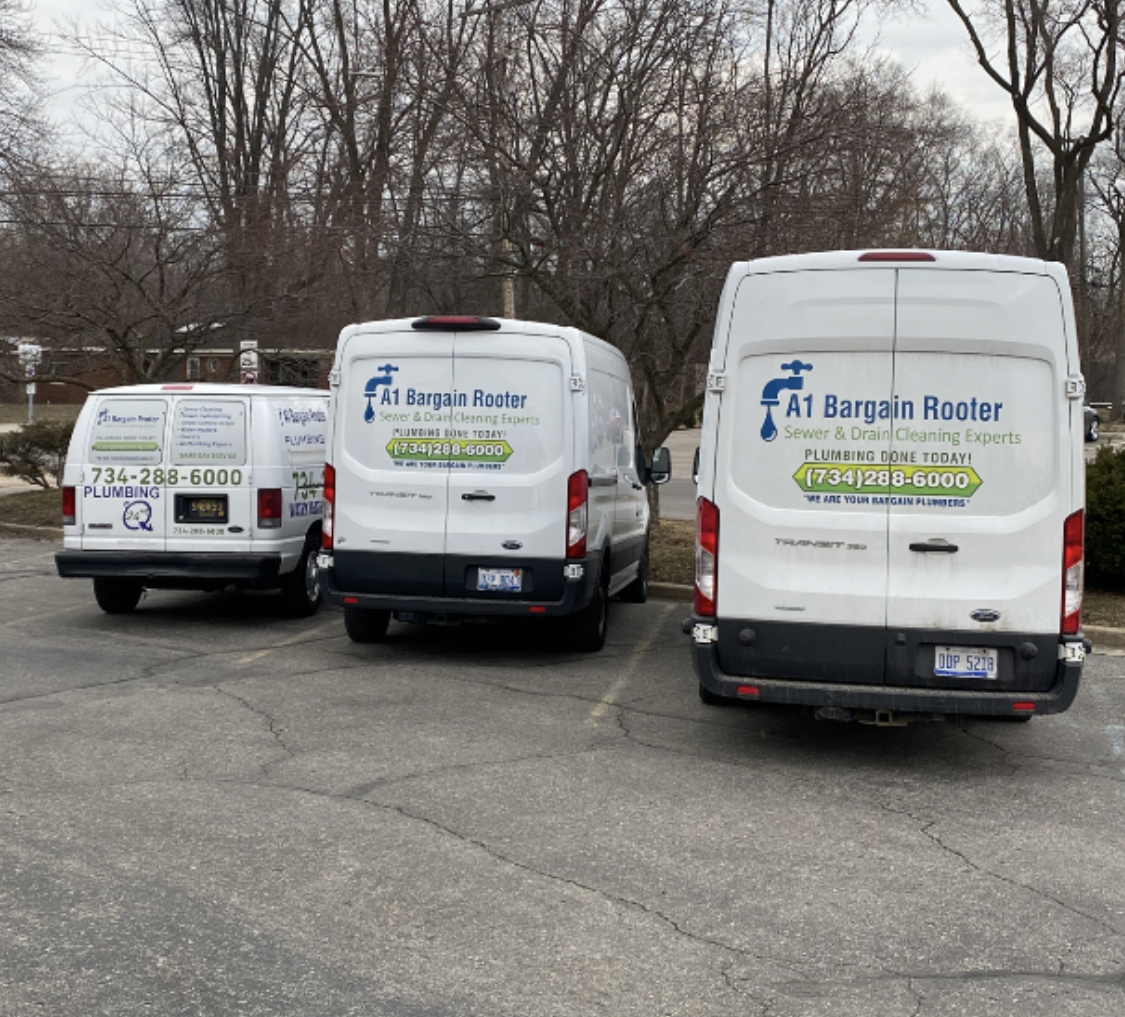 Three white vans are parked in a parking lot and one of them says at bargain rotter on the back