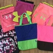 A collection of Under Armour cinch sacks and bags in various bright colors, including pink, purple, blue, and black.