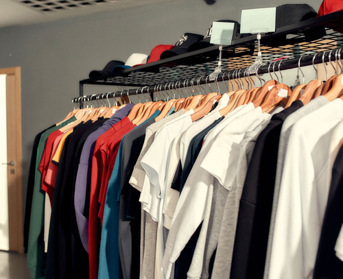 Clothing rack with assorted T-shirts and hats in a store or closet room